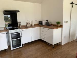 a kitchen with white cabinets and a stove top oven at Coed Bach Suite in Bryngwran