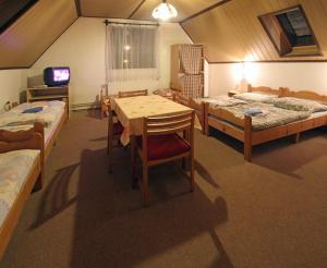 a room with three beds and a table and a tv at Privat Lucia in Nová Lesná