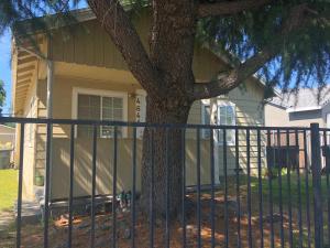 una cerca frente a una casa con un árbol en WHOLE Family - WholeVille en Sacramento