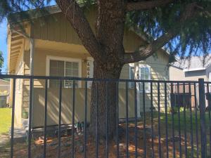 a fence in front of a house with a tree at WHOLE Family - WholeVille in Sacramento