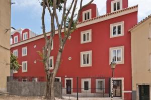 un edificio rojo con un árbol delante de él en Vila Olarias, en Lisboa