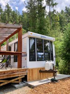 a tiny house with a porch and a deck at Garden Bay Hideaway - Glamping in Garden Bay