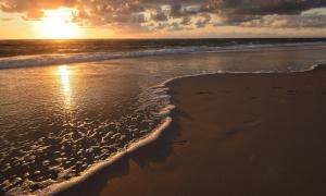 un coucher de soleil sur une plage avec la marée arrivant dans l'établissement "Stine", à Westerland