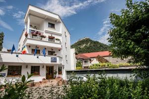 a white building with a balcony and a mountain at Pensiunea Vila Europa in Deva