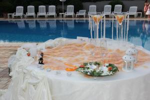 un tavolo con bicchieri da vino e un piatto accanto a una piscina di Hotel Delle Canne ad Amantea