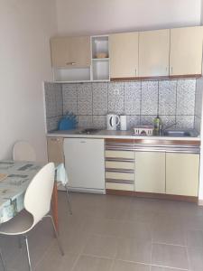 eine Küche mit weißen Schränken sowie einem Tisch und Stühlen in der Unterkunft Apartmani Atila Damir in Omiš