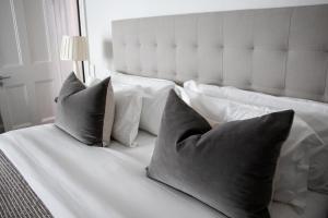 ein weißes Bett mit vier Kissen darauf in der Unterkunft Heritage House in Stellenbosch