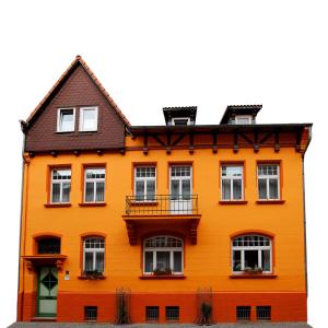 ein orangenes Haus mit weißen Fenstern an der Seite in der Unterkunft Ferienwohnungen Salzwedel Weissbach in Salzwedel