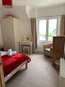 a bedroom with a red bed and a window at Postmans Rest, second floor apartment, Lynmouth with private parking in Lynmouth