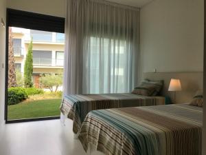 two beds in a bedroom with a large window at Cavalo Preto Luxury Beach Resort in Quarteira
