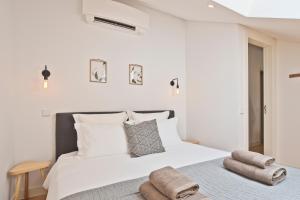 a bedroom with a large white bed with towels on it at Vila Olarias in Lisbon