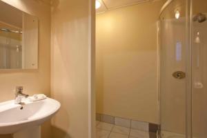 a bathroom with a shower, sink, and mirror at Auckland Airport Kiwi Motel in Auckland