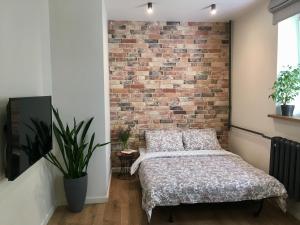 a bedroom with a brick wall and a bed at Apartment Desyatinnaya in Velikiy Novgorod