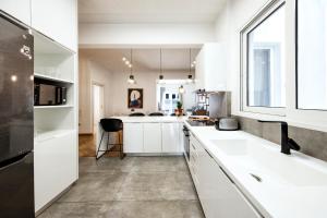 eine Küche mit weißen Schränken und einem großen Fenster in der Unterkunft Kolonaki Square Executive Apartment in Athen