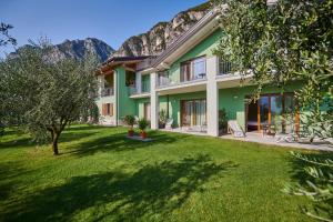 uma casa verde com montanhas ao fundo em Maso Tobel Riva del Garda em Riva del Garda