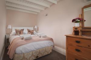 a bedroom with a bed with a dresser and a mirror at Crow Hall - Luxury Holiday Accommodation in Reeth