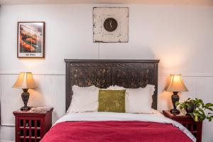 a bedroom with a large bed with red sheets and two lamps at Jonquil Motel in Bisbee