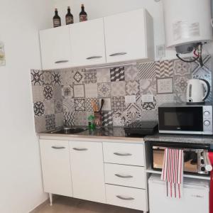 eine Küche mit weißen Schränken und einer Mikrowelle in der Unterkunft El Balconcito Monoambiente in Saladillo