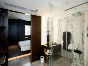 a bathroom with a glass shower and a bedroom at CitiGO Hotel (Shanghai International Tourist Resort) in Shanghai