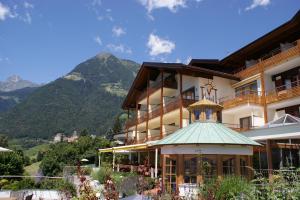 un grand bâtiment avec des montagnes en arrière-plan dans l'établissement Marini's giardino Hotel, à Tirolo
