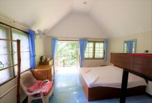 a bedroom with a bed and a chair and a window at Poseidon Bungalows in Khao Lak