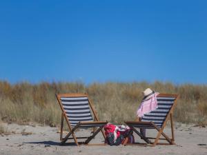 - deux chaises de plage assises sur le sable sur la plage dans l'établissement Pacific Park Christian Holiday Camp, à Papamoa