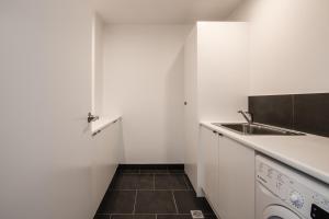 a white kitchen with a sink and a dishwasher at Change Overnight in Launceston