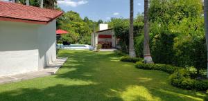 un patio con césped verde y una casa y una piscina en Casa cerca de las Estacas en Ticumán