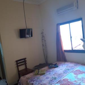a bedroom with a bed and a window and a tv at La Javanaise Home Stay Malioboro in Yogyakarta