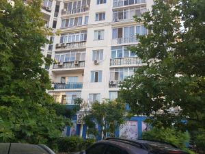 um edifício de apartamentos branco alto com varandas e árvores em Апартаменты на Люстдорфской em Odessa