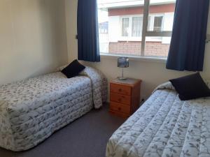 a bedroom with two beds and a window at AAA Thames Court Motel in Oamaru