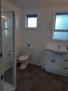 a bathroom with a toilet, sink, and tub at AAA Thames Court Motel in Oamaru
