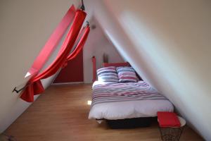 een slaapkamer met een bed op een zolder met rode gordijnen bij P'tit Biscuit in Riquewihr