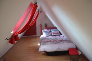 1 dormitorio con 1 cama en un ático con cortinas rojas en P'tit Biscuit, en Riquewihr