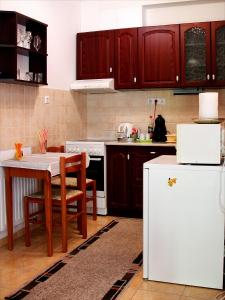 a kitchen with a table and a white refrigerator at Inci apartman in Pécs