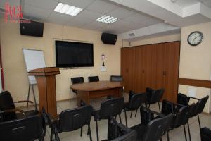 einen Konferenzraum mit einem Tisch, Stühlen und einer Uhr in der Unterkunft Гостиница Русь in Barnaul