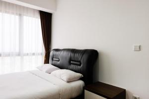 a bedroom with a bed with a black leather headboard at 1BR Apartment at M-Town Residence near Summarecon Mall Serpong By Travelio in Tangerang +11 photos