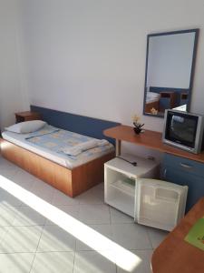 a small bedroom with a bed and a tv at Blue House - Синята къща in Obzor