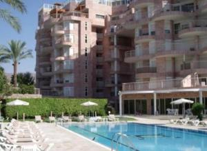 a hotel with a swimming pool and chairs and a building at Sweethome26 EILAT Apt with Jaccuzzi / Free Parking in Eilat