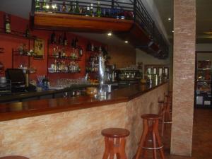 eine Bar mit drei Hockern und einer Theke mit Flaschen in der Unterkunft Pensión Cangas de Onis in Siero