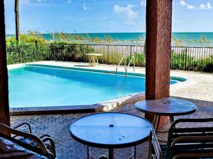 a swimming pool with two tables and chairs and the ocean at Madeira Towers 601 Beach front with spectacular views 533 in St. Pete Beach