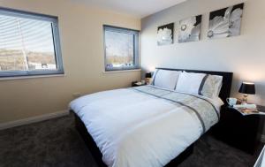 een slaapkamer met een groot wit bed en 2 ramen bij Valley Lodge in Trearddur