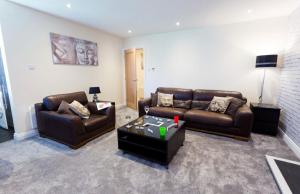 a living room with two couches and a table at Valley Lodge in Trearddur