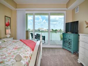 een slaapkamer met een bed, een televisie en een balkon bij Sandpiper's Cove 303 Waterfront 3 Bedroom 2 Bathroom - Sandpiper's Cove 23146 in Clearwater Beach