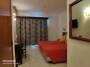 ein Hotelzimmer mit einem roten Bett und einem Spiegel in der Unterkunft Hotel Alnacir in Faro