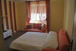 a bedroom with a bed and a couch and a window at Suites And Chalets Laghi & Monti in Ornavasso