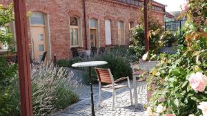 a table and chair in a garden with a brick building at Maison am Liesingbach in Vienna