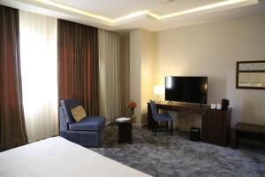 a hotel room with a bed and a desk with a television at The Town Hotel Doha in Doha