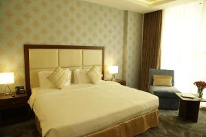 una camera con un grande letto bianco e una sedia di The Town Hotel Doha a Doha
