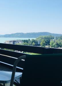 a chair sitting on a balcony with a view of the water at MyRiviéra Apartman in Balatonfüred